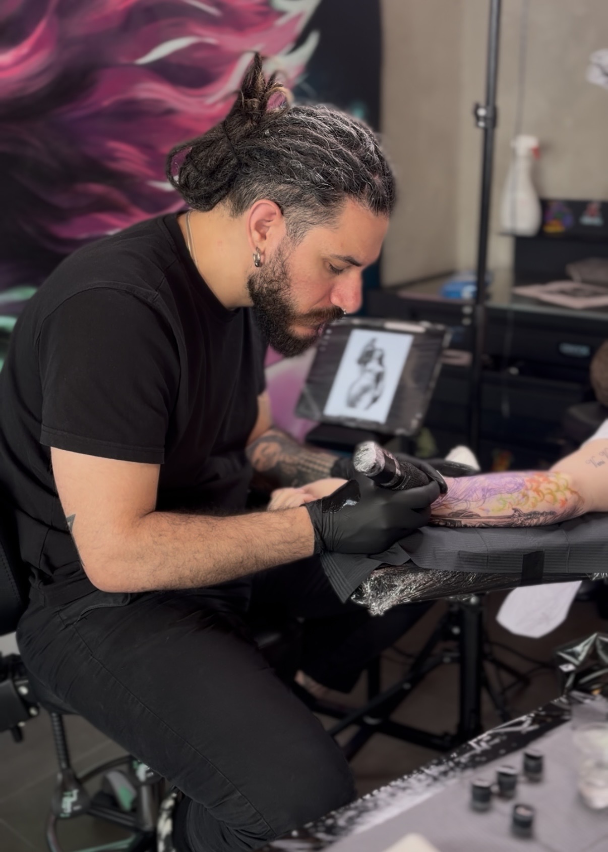 Tatuerare arbetar på färgglad ärmtatuering